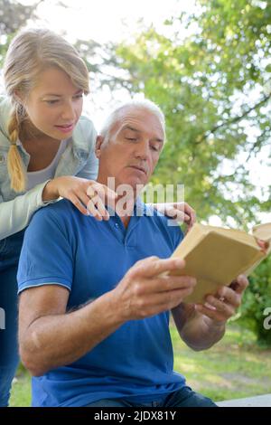 smiling worker reading book with older man Stock Photo