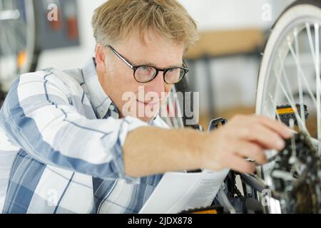 handyman fixing bike wheel in his garage Stock Photo