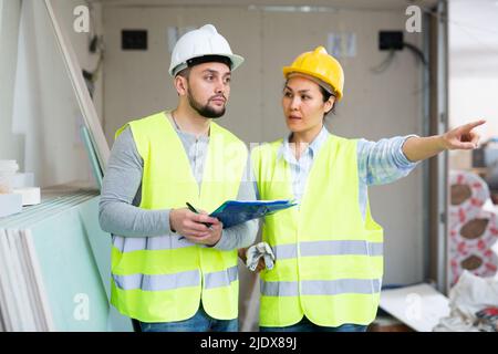 Two architects with papers discussing workflow at construction site Stock Photo