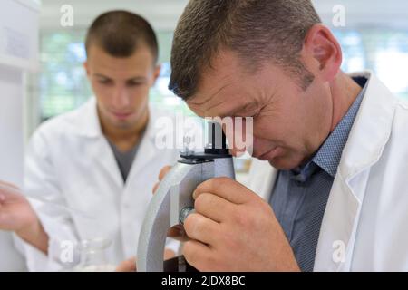confident researcher adjusting microscope to examine chemical substance Stock Photo