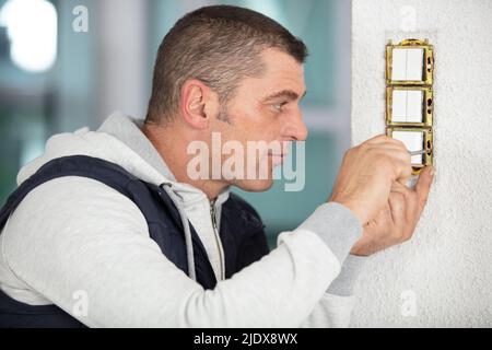 electrician installing new current socket with screwdriver Stock Photo