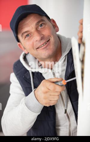 young handyman repair window with screwdriver Stock Photo