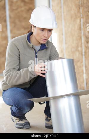 female worker fitting ventilation system in buildings ceiling Stock Photo