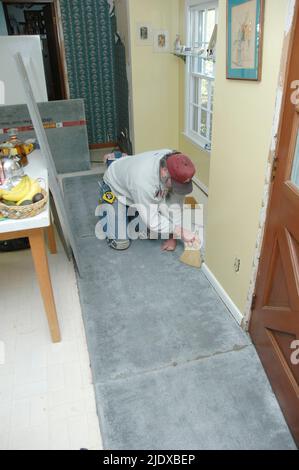 Do it yourself home owner Putting down underflooring and mastic and tile on remodeling of older home with tile floors Stock Photo
