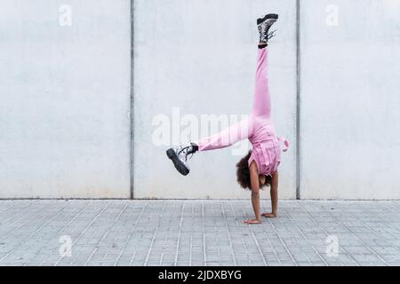 Carefree girl practicing handstand in front of wall Stock Photo