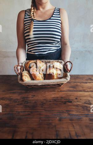 Bakery owner holding bread basket on table Stock Photo