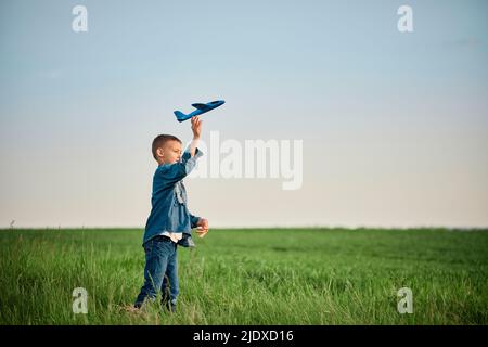 Boy throwing airplane toy in field on weekend Stock Photo