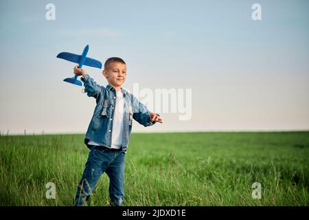 Boy playing with model on airplane in meadow Stock Photo