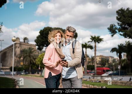 Mature man using smart phone by woman in city Stock Photo