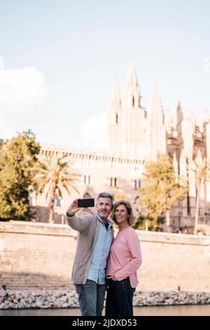 Mature couple taking selfie on smart phone in city Stock Photo