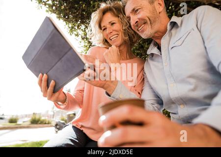 Happy mature couple using tablet computer in park Stock Photo