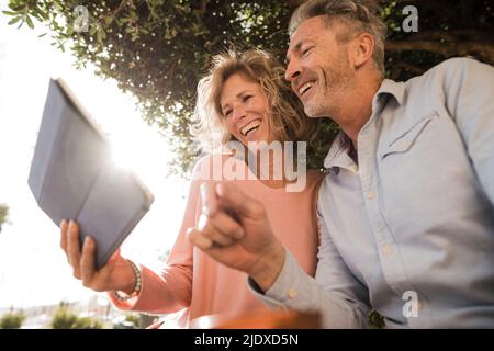 Cheerful mature couple using tablet PC in park Stock Photo