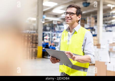 Smiling worker with tablet PC standing in warehouse Stock Photo