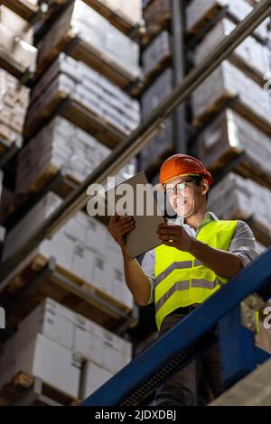 Smiling worker wearing eyeglasses using tablet PC working in warehouse Stock Photo