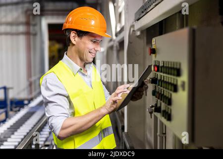 Smiling worker using tablet PC by control panel in warehouse Stock Photo