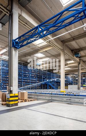 Cardboard boxes by conveyor belt in warehouse Stock Photo