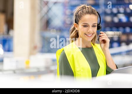 Happy worker talking through headset working in warehouse Stock Photo