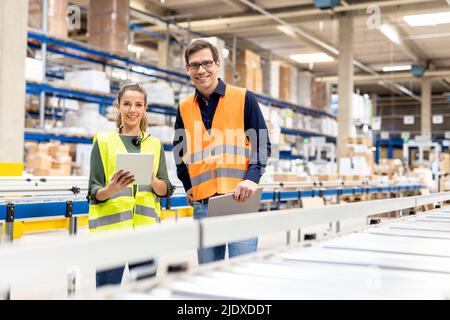 Smiling workers with tablet PC standing together in warehouse Stock Photo