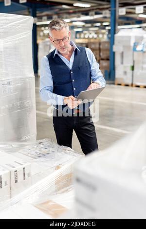 Manager checking inventory through tablet PC in warehouse Stock Photo
