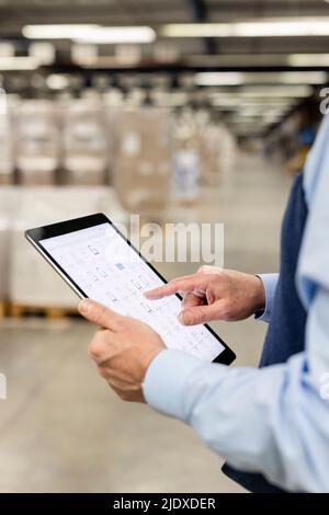 Manager analyzing list through tablet PC in warehouse Stock Photo