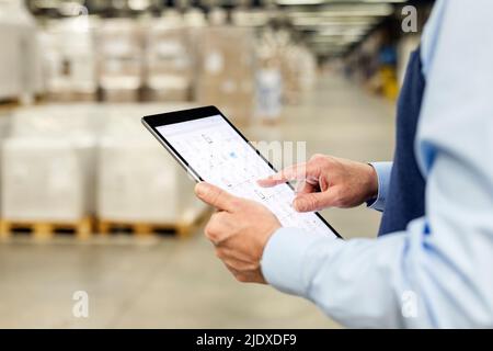 Hands of manager checking list through tablet PC in warehouse Stock Photo