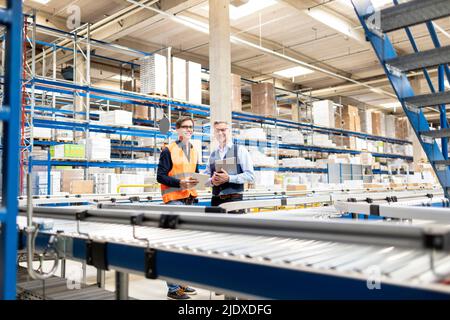 Smiling worker and manager standing with tablet PC in warehouse Stock Photo