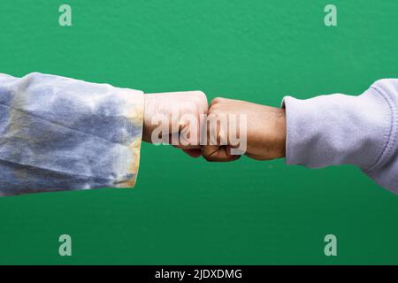 Hands of friends bumping fists in front of green wall Stock Photo