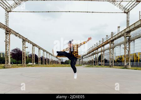 Happy young man jumping on footpath Stock Photo