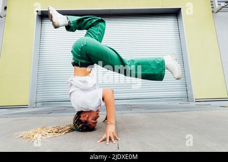 Young woman doing headstand in front of shutter Stock Photo