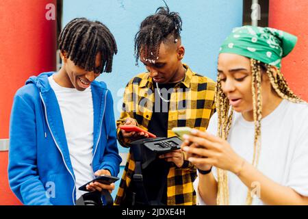 Happy young men and woman using smart phones Stock Photo