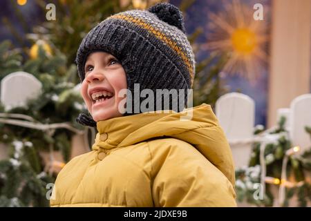 Happy boy in yellow padded jacket wearing knit hat Stock Photo