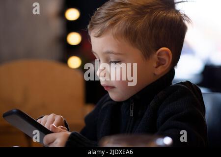 Cute boy using smart phone in winter Stock Photo