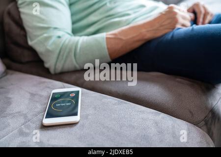 Smart phone with timer by man sitting on sofa at home
