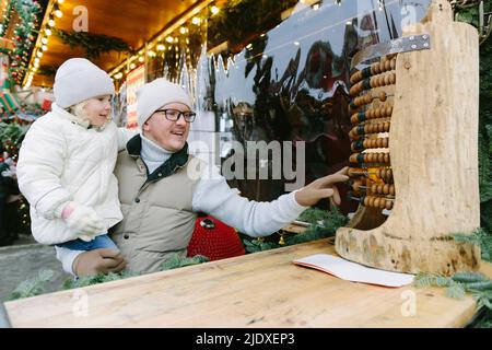 Father and daughter playing with abacus at Christmas market Stock Photo