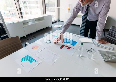 Businessman examining charts and graphs at desk in office Stock Photo