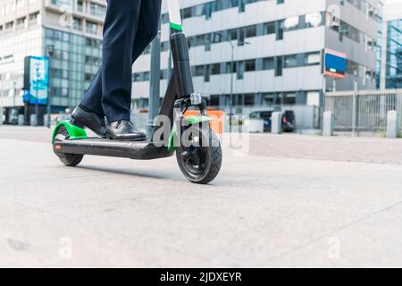 Businessman riding electric push scooter on footpath Stock Photo