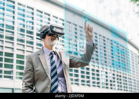 Businessman wearing wearing VR glasses touching virtual screen Stock Photo