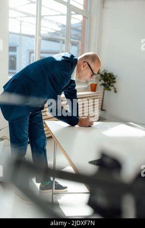 Businessman writing on document at desk Stock Photo