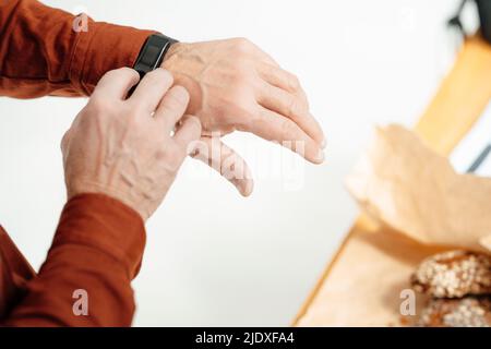 Hand of businessman touching smart watch in office Stock Photo