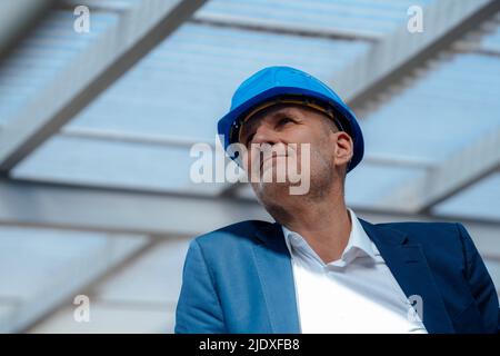 Senior businessman wearing hardhat at construction site Stock Photo
