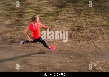 Young woman running on dirt road Stock Photo