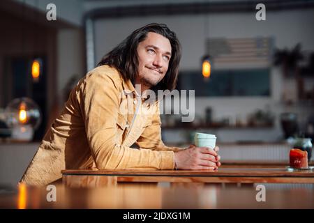 Happy man with coffee cup leaning on table at coffee shop Stock Photo