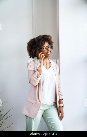 Smiling woman talking on phone at workplace Stock Photo