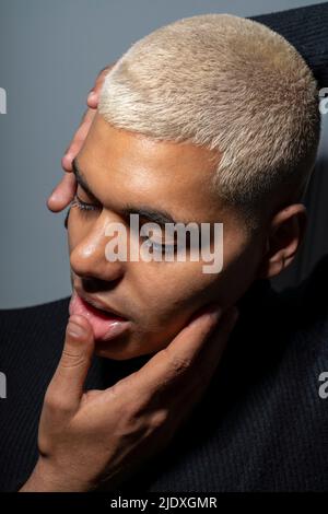 Man with head in hands against gray background Stock Photo
