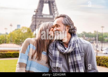 Mature woman kissing boyfriend in front of Eiffel tower, Paris, France Stock Photo