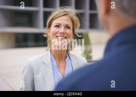 Smiling mature businesswoman discussing with colleague Stock Photo