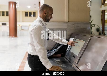 Man using touch screen computer standing in hotel Stock Photo