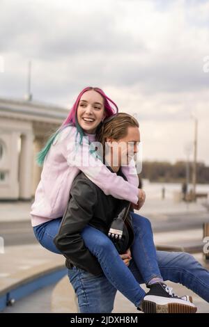 Happy man giving piggyback ride to girlfriend Stock Photo