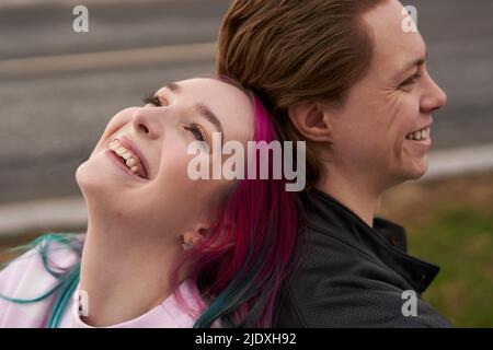Happy young couple leaning back to back on each other Stock Photo