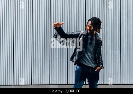 Young man gesturing in front of wall Stock Photo